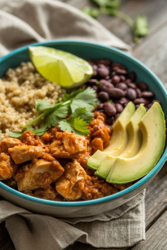 Chipotle honey chicken bowl with black beans, avocado, quinoa, and lime wedges