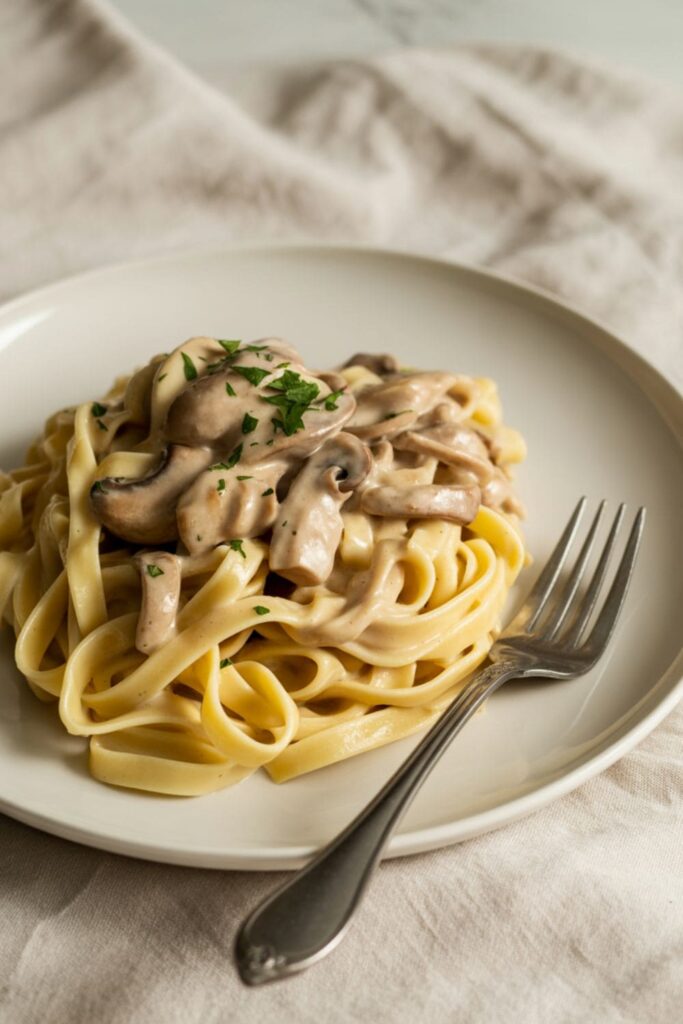 Creamy mushroom sauce with shredded chicken served over pasta and garnished with herbs