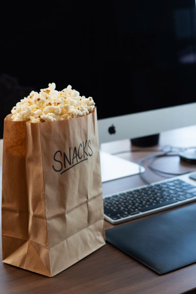 Lightly salted popcorn spilling from a paper bag onto a napkin near a keyboard
