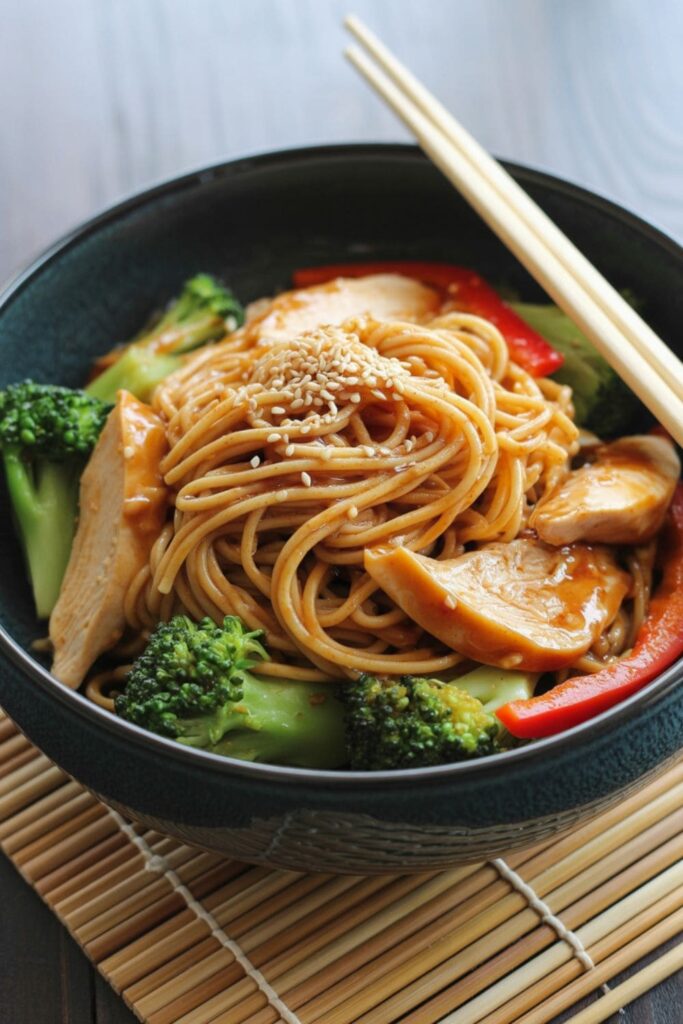 Teriyaki chicken noodle bowl with soba noodles, stir-fried vegetables, and sesame seeds